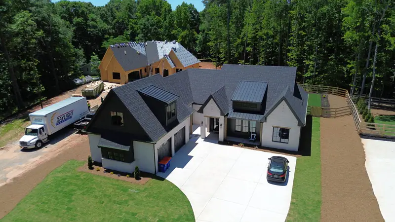 Aerial view of a large new construction home with a new dark architectural shingle roof