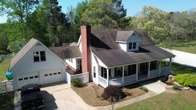 Before: worn, faded shingle roof on a white farmhouse with a wraparound porch in North Georgia