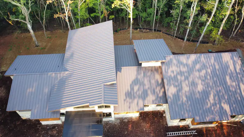 Aerial view of a silver standing seam metal roof installation on a new home