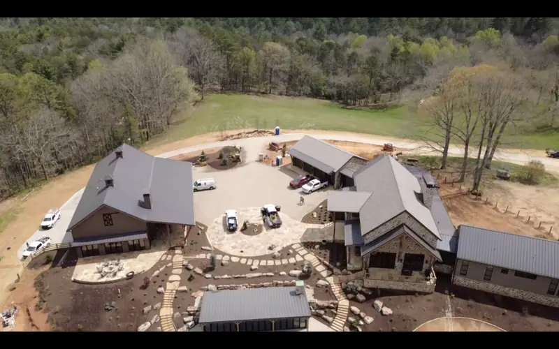 Drone still of a white farmhouse with a new charcoal shingle roof and wraparound porch